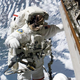 Astronaut at International Space Station doing spacewalk repairs with Earth in background